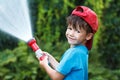 Boy in cap pours water outdoor