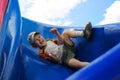 The boy in the cap sliding on the blue children`s slide