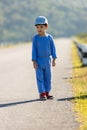 A boy in a cap standing in the middle of the highway in the field. boy alone in the street. Child standing in of the road. Royalty Free Stock Photo