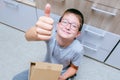 A boy with a cardboard box, package, parcell showing a thumb up gesture, good delievery and shipping concept Royalty Free Stock Photo