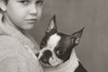 The boy cares, loves and tenderly embraces his devoted friend the Boston Terrier dog. Black and white photo. Royalty Free Stock Photo