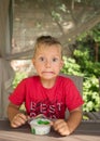 boy with cartoonish big displeased grimace and wide-open eyes with funny expression is tasting milk yogurt