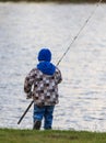 The boy catches fish on the pond at sunset Royalty Free Stock Photo