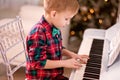 Boy in a checkered shirt and tie butterfly playing piano. Christmas concept