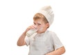 A boy in chef clothes drinks milk from a glass while cooking an apple p Royalty Free Stock Photo