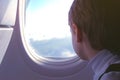 Boy chews gum and looks out the window at the clouds when landing the plane. Royalty Free Stock Photo