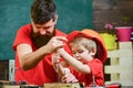 Boy, child busy in protective helmet learning to use screwdriver with dad. Teamwork and assistance concept. Father Royalty Free Stock Photo