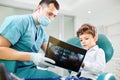 Boy child and dentist look at x-ray image