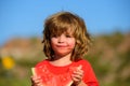 Boy child eating watermelon with funny face, green nature background. Close-up photo of kids eating sweet red melon. Royalty Free Stock Photo