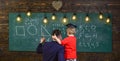 Boy, child in graduate cap listening teacher, chalkboard on background, rear view. Teacher with beard, father teaches Royalty Free Stock Photo
