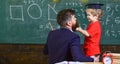 Boy, child in graduate cap listening teacher, chalkboard on background, rear view. Favourite teacher concept. Teacher