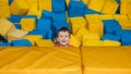 A boy child plays in a pool with soft cubes,. A child in a game entertainment children& x27;s room.