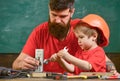 Boy, child in protective helmet makes by hand, repairing, does crafts with dad. Father with beard and little son in