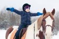 A boy child rides a horse in winter through a snowy forest Royalty Free Stock Photo