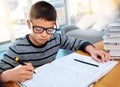 Boy child, student and writing in book for studying, education and learning homework on table at home. Smart little kid Royalty Free Stock Photo