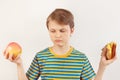 Boy chooses between sandwich and fresh apple on white background Royalty Free Stock Photo