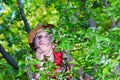 The boy climbed on an apple tree in a hat and thought about it.