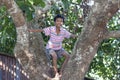 The boy climbing on the big tree and standing smile on the trunk in the countryside. Royalty Free Stock Photo