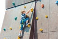 A boy in climbing equipment conquers the top of an artificial tower for climbers in a sports extreme recreation park