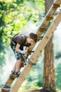 Boy climbing ladder with equipment in adventure rope park Royalty Free Stock Photo