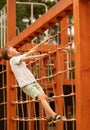 boy climbing on a rope ladder in a children's playground Royalty Free Stock Photo