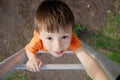 Boy climbing stairs and playing outdoors on playground, children activity. Child portrait from above. Active healthy con