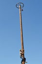 Boy climbing up on wooden slippery column to take the red woman boots