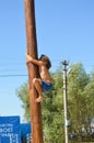 Boy climbing up on wooden slippery column to take the red woman boots