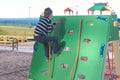 Boy climbs on a climbing wall holding the rope on the Playground. Royalty Free Stock Photo