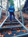 Boy climbs an outdoor steel staircase to the rocky viewpoint of the ruins of fortress