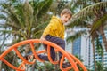 The boy climbs on the playground against the background of palm trees Royalty Free Stock Photo