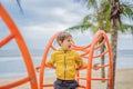 The boy climbs on the playground against the background of palm trees Royalty Free Stock Photo