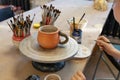 Kid painting ceramic cup on a Potter's wheel at workshop