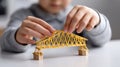 Boy Constructs Model Bridge with Yellow Straws and Wooden Blocks Royalty Free Stock Photo