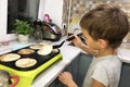 Boy is cooking pancackes by himself without parents help. Royalty Free Stock Photo