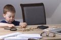 The boy counts and lays out money on a wooden table. Royalty Free Stock Photo