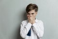 The boy covered his mouth with his hands. Emotional child in a white shirt on a background of a gray wall. Fear and horror Royalty Free Stock Photo