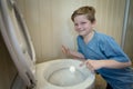 Boy covering a toilet with plastic as a prank