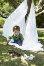 Boy Crawling Out Of Sheet Tent In Backyard Royalty Free Stock Photo