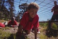 Boy crawling under the net during obstacle course training Royalty Free Stock Photo