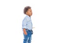 Boy with curly hair in jeans and a light-colored shirt is standing in a half-turn holding a pencils in both hands and Royalty Free Stock Photo