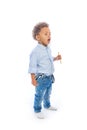 Boy with curly hair in jeans and a light-colored shirt is standing in a half-turn holding a pencils in both hands and Royalty Free Stock Photo