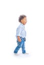 Boy with curly hair in jeans and a light-colored shirt is standing in a half-turn holding a pencils in both hands and Royalty Free Stock Photo