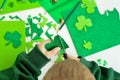 DIY St.Patricks Day decor. A boy cuts with scissors craft card of shiny green paper. Selective focus Royalty Free Stock Photo