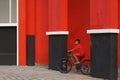 A boy cycling alone on a road between a concrete pillar and a red wall in Pandaan City, photo taken in Pasuruan 2020 Indonesia Royalty Free Stock Photo