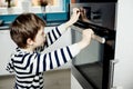 Boy dangerously playing with the knobs on the oven Royalty Free Stock Photo