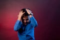 The boy is dark in a blue shirt on a purple and maroon background Royalty Free Stock Photo