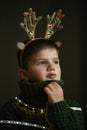 Boy with deer horns for Christmas, hides his face in a collar as in mask