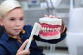 A boy at a dentist`s appointment learns to brush his teeth correctly. Portrait of a boy in a dental office. A toothbrush and a