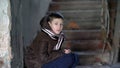 Boy in depression, looking at the camera, hiding from the cold in an old dilapidated house Royalty Free Stock Photo